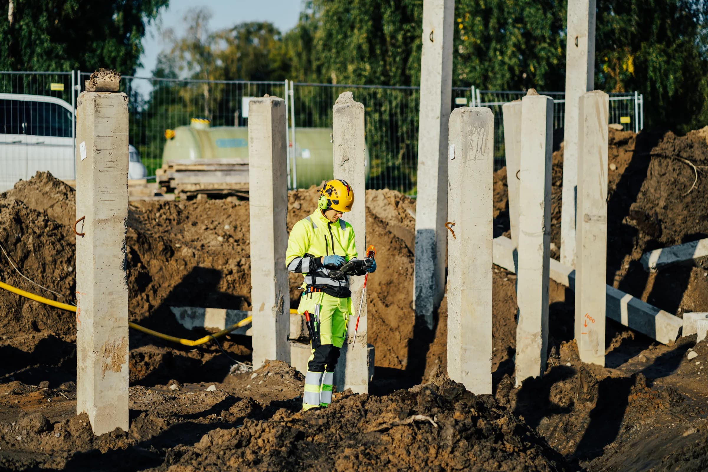 Mättekniker mäter in betongpelare på en byggarbetsplats