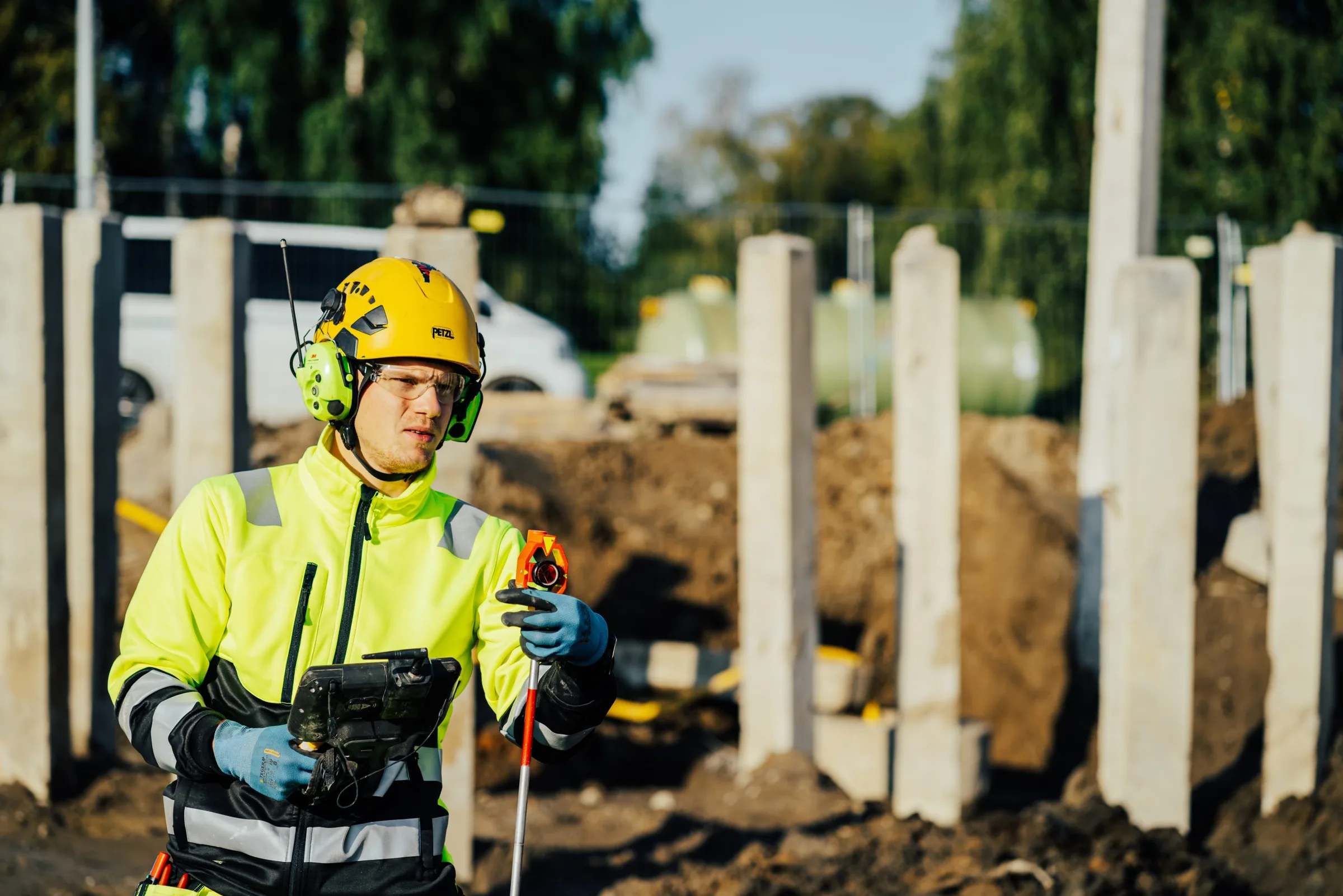 Mättekniker med fältdator vid betongpelare på en byggarbetsplats