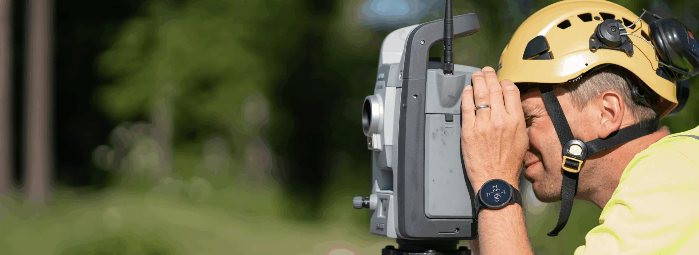 Mättekniker med gul hjälm siktar genom en totalstation