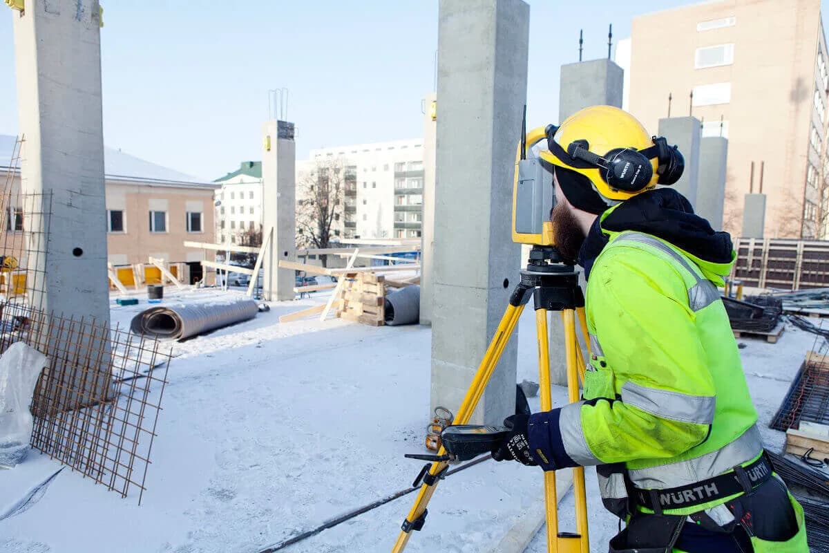 Mättekniker med totalstation på en byggarbetsplats vintertid